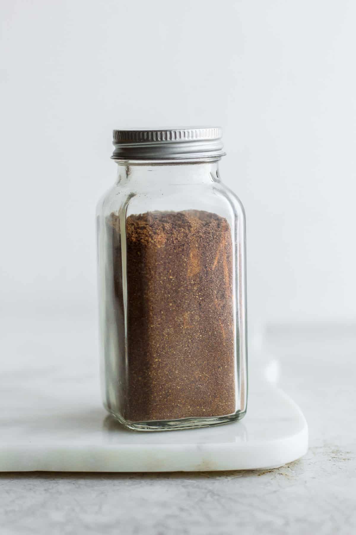 Lebanese 7 Spice in glass spice jar with some of the spice spilled