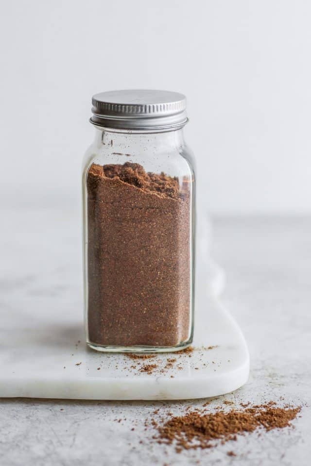 Lebanese 7 Spice in glass spice jar with some of the spice spilled