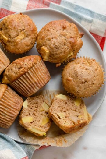 Plate of apple cinnamon muffins with one cut in half to show the apple pieces