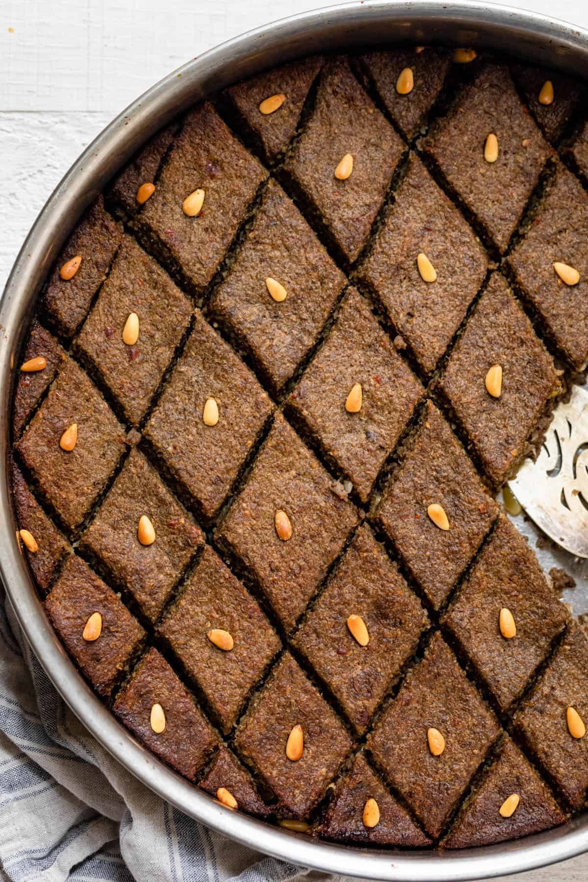 Baked kibbeh (also called kibbeh bil sanieh) topped with pine nuts