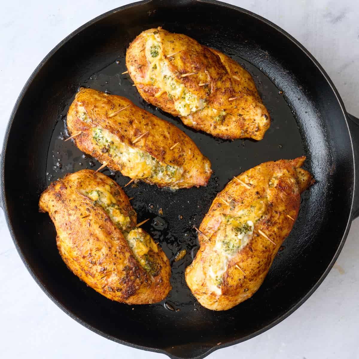 Stuffed chicken breasts in a skillet after cooking.