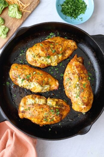 Broccoli and cheese stuffed chicken breast in the skillet garnished with chopped parsley.