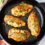 Broccoli and cheese stuffed chicken breast in the skillet garnished with chopped parsley.