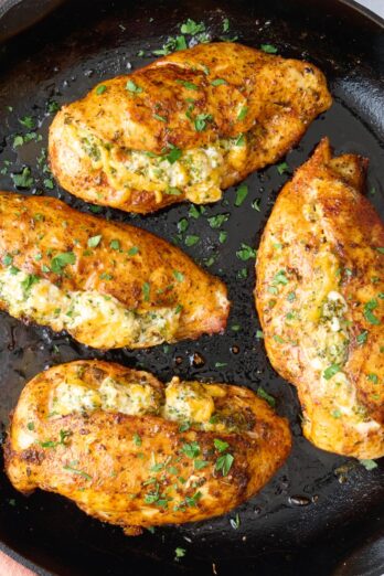 Broccoli and cheese stuffed chicken breast in the skillet garnished with chopped parsley.