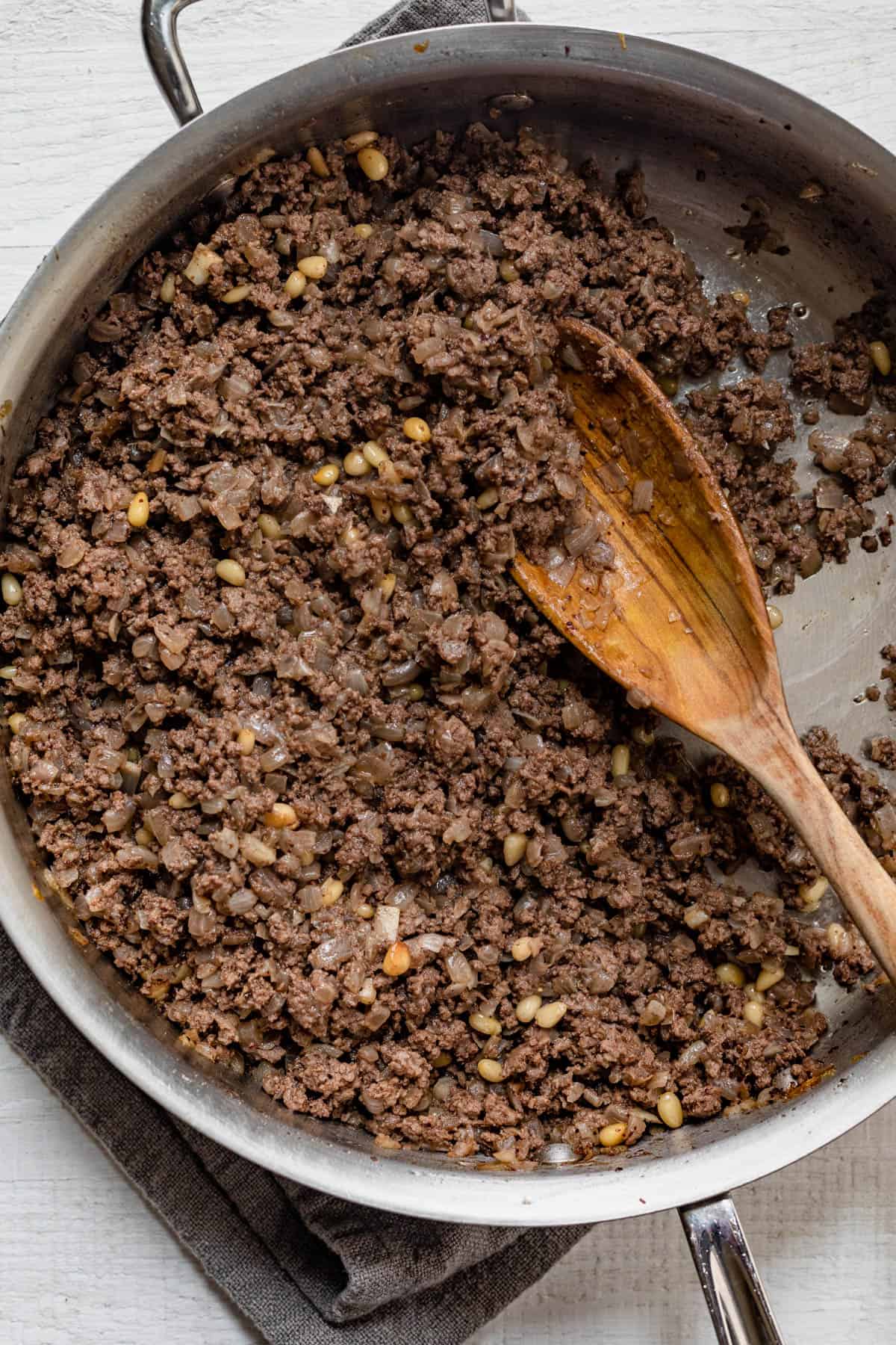 Large pan of cooked ground beef with onions and pine nuts