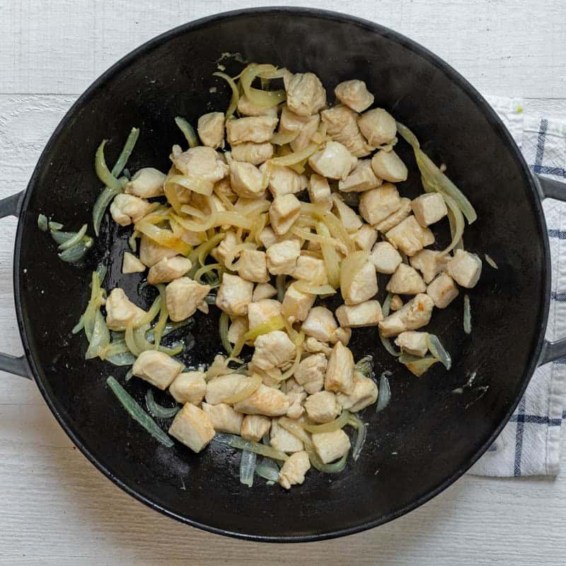 Cooked chicken and onions in pot.