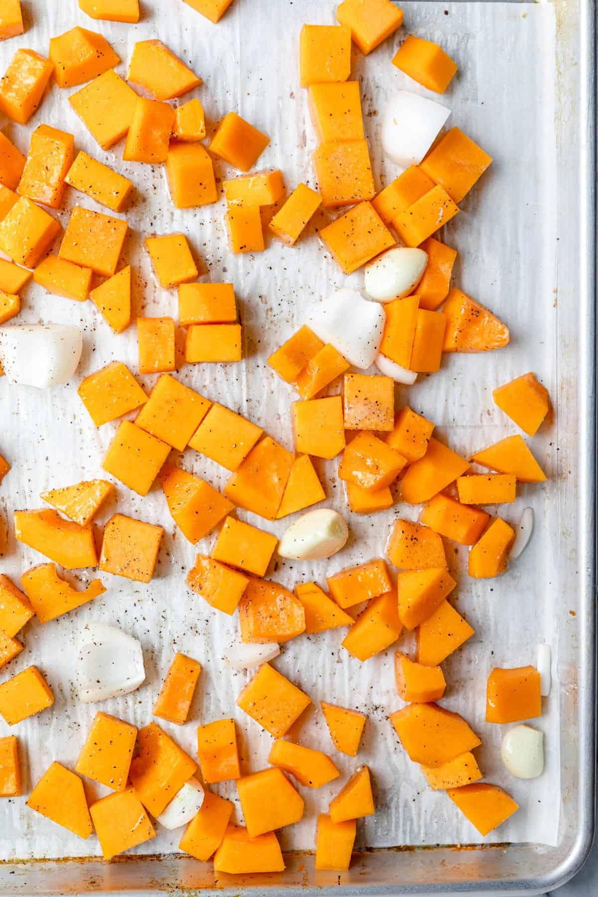Butternut squash, onions, and garlic on a baking sheet.