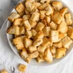 Homemade croutons in a large bowl with a couple fallen out