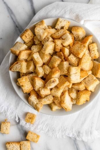 Homemade croutons in a large bowl with a couple fallen out