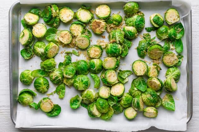 Brussel sprouts on a pan with the seasoning before baking