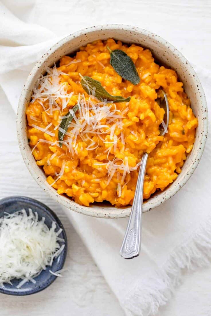 Pumpkin risotto in a small bowl with parmesan cheese on the side