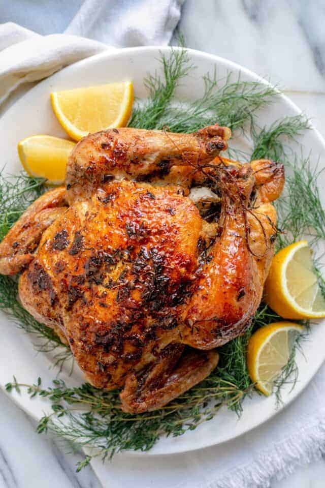 White plate with roasted chicken with lemon and herbs