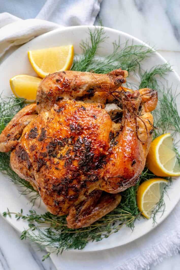 White plate with roasted chicken with lemon and herbs