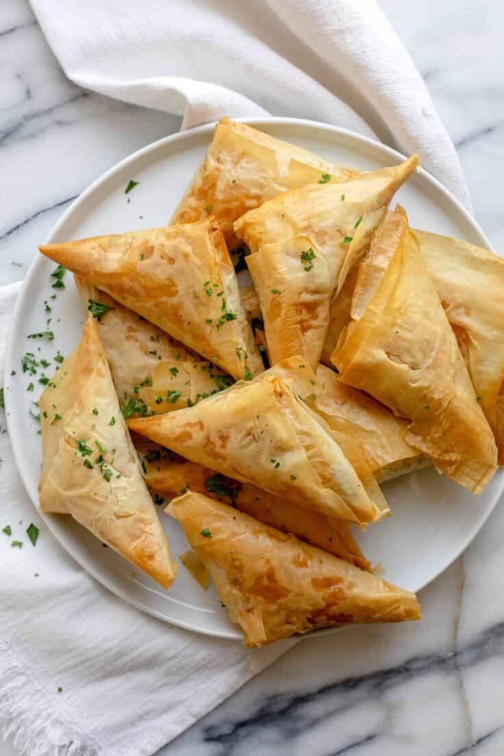 Greek spanakopita recipe made into triangles on a white plate