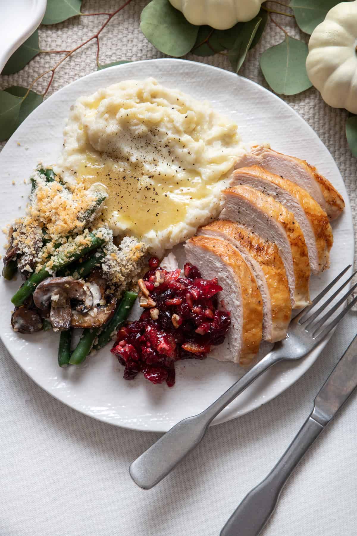 Plate at thanksgiving with turkey, mashed potatoes, cranberry and green beans