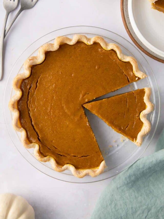 Pumpkin pie with slices cut out on a round glass baking dish