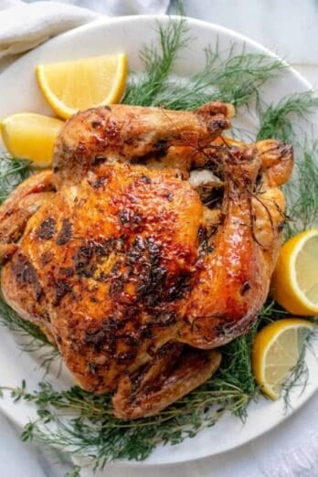 White plate with roasted chicken with lemon and herbs