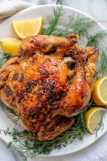 White plate with roasted chicken with lemon and herbs