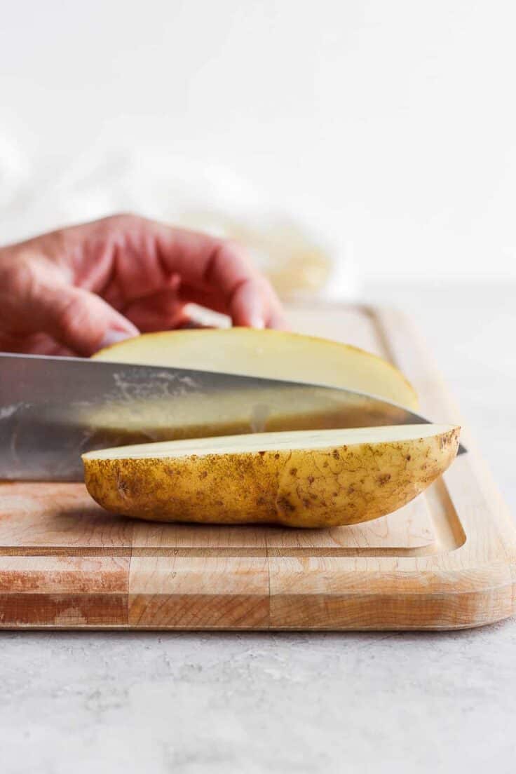 Cutting board with large potato being cut