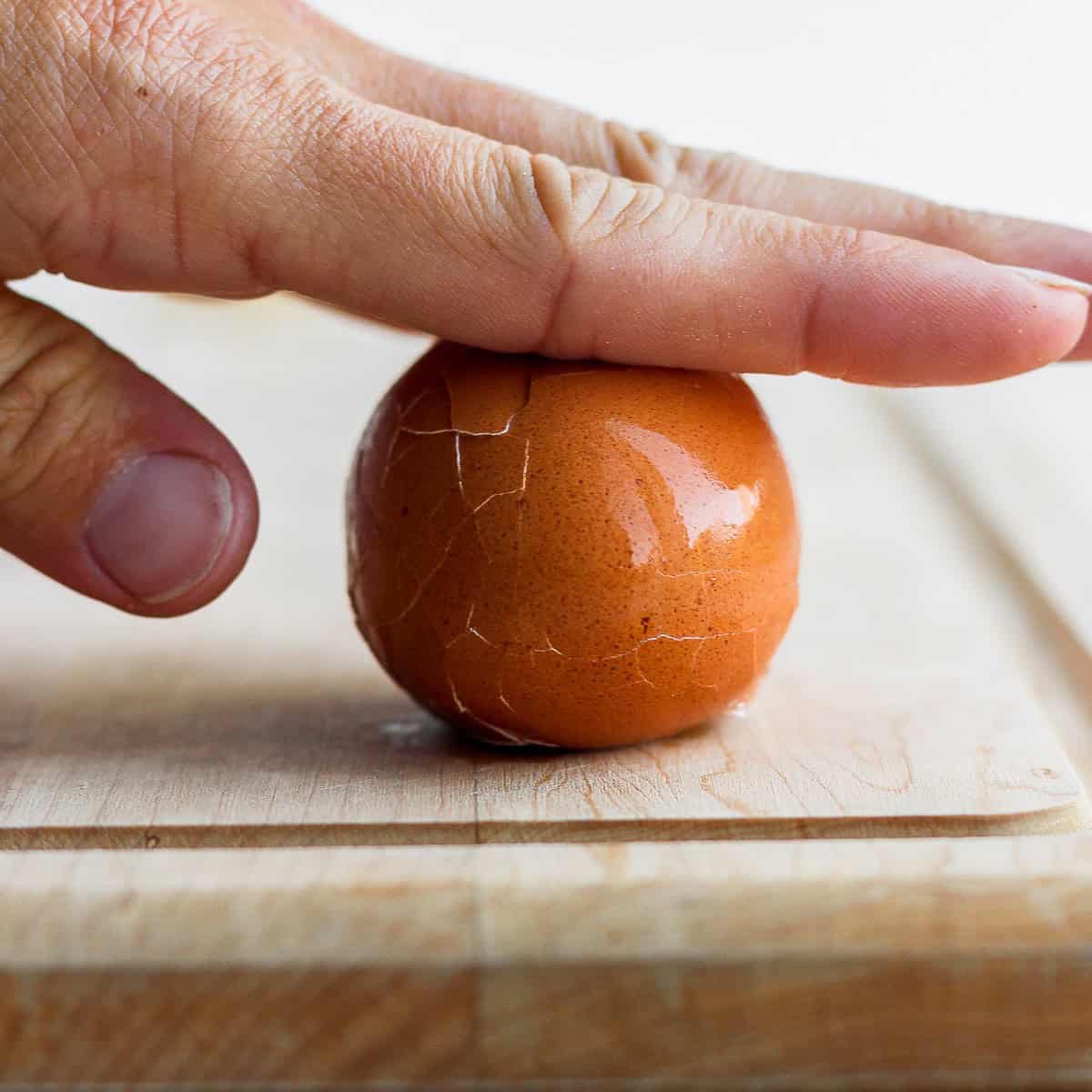 Hand rolling egg on cutting board.