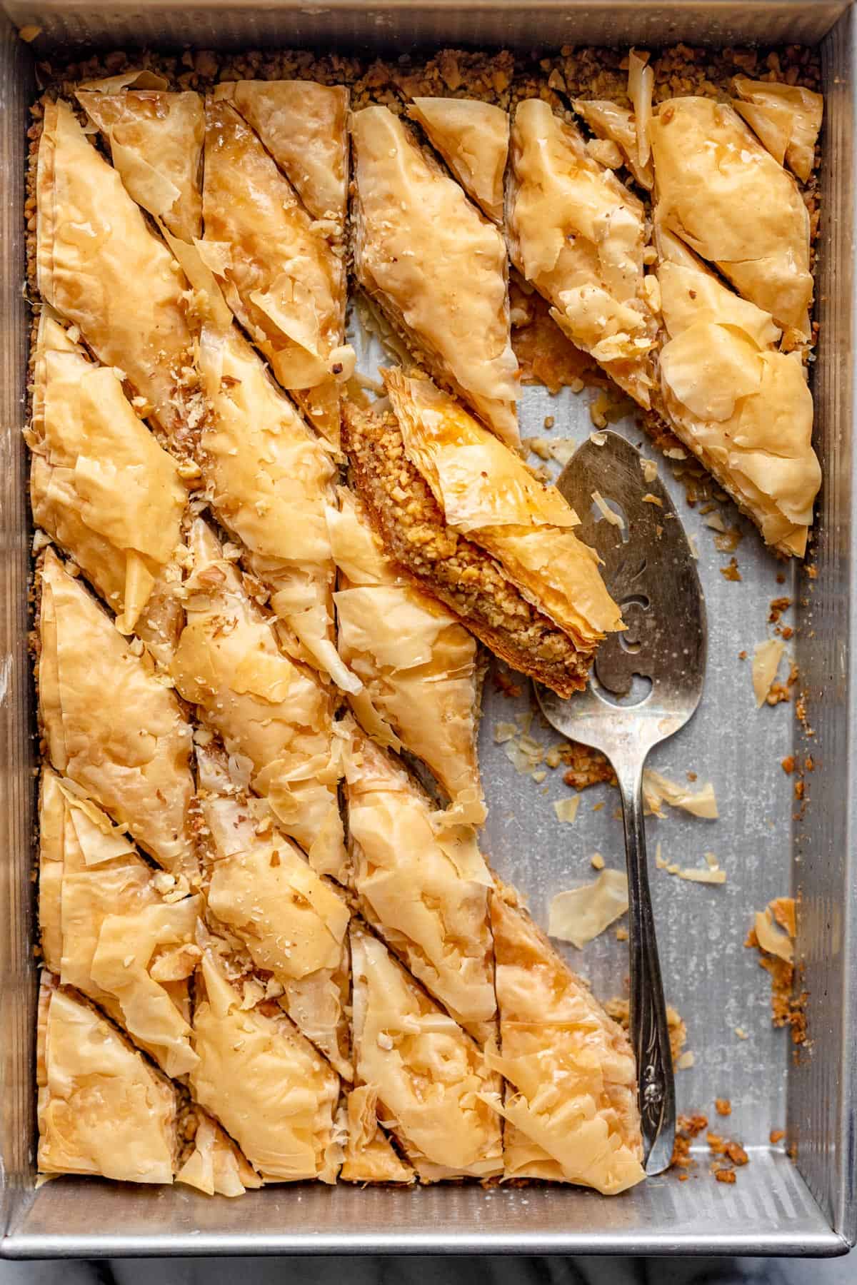 Baklava in einem Tablett nach dem Abkühlen und mit einem Spatel in das Tablett schneiden