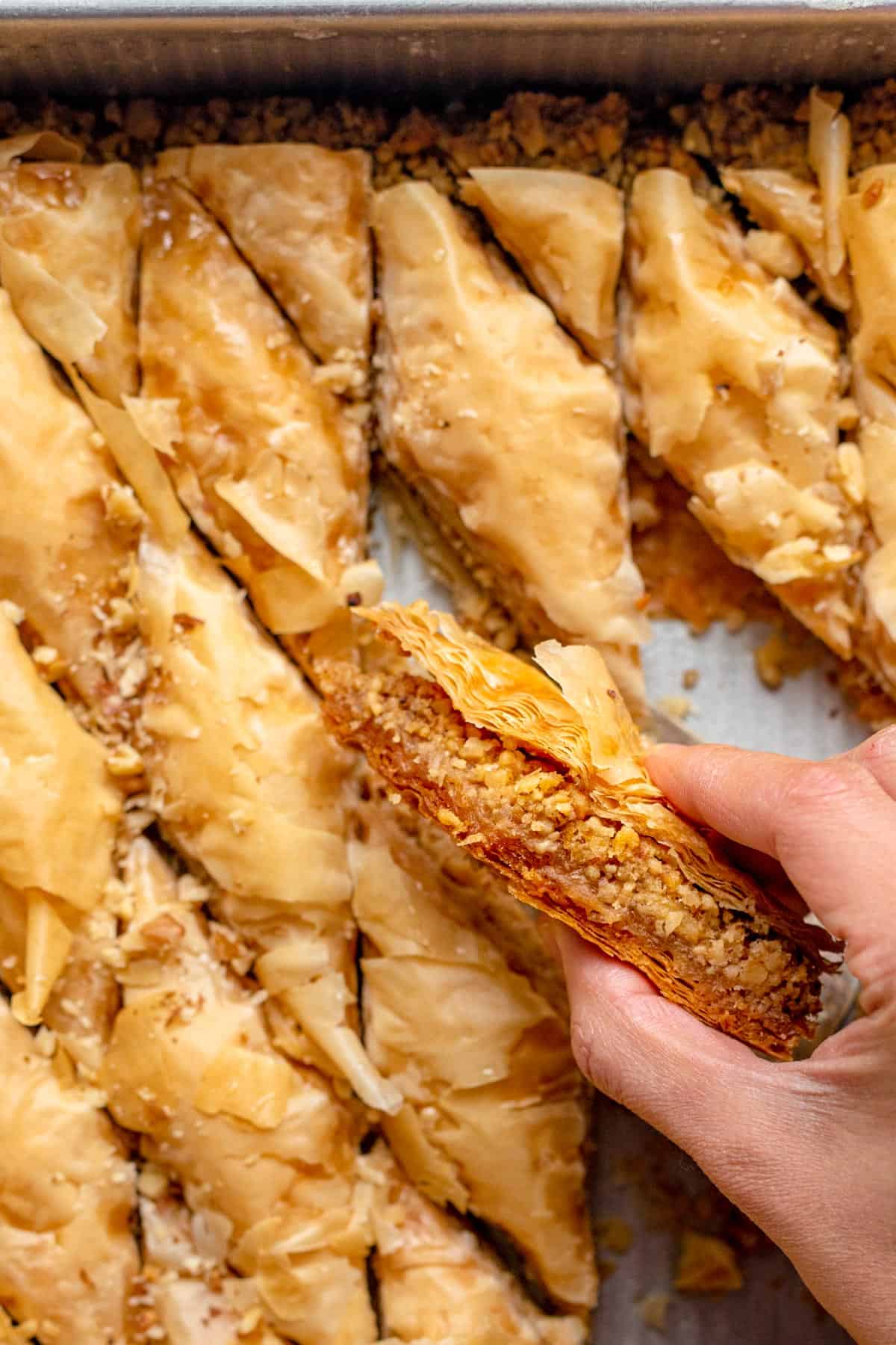 Hand, die ein Stück libanesisches Baklawa hält, um das Innere des Stücks zu zeigen