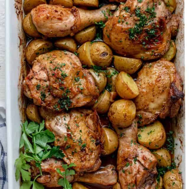 Chicken and potatoes in a pan garnished with parsley