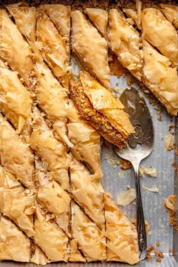 Baklava in a tray after cooled and cut into with spatula in tray