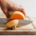 Butternut squash on cutting board getting cut