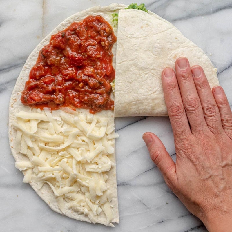 Folding egg quarter on top of avocado corner.