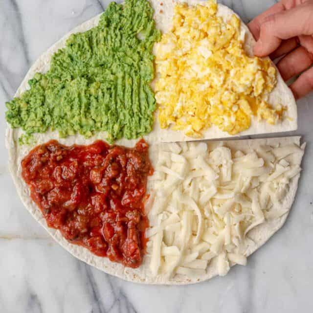 Tortilla with four quarters stuffed with eggs, cheese, salsa, and avocado