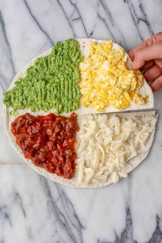 Tortilla with four quarters stuffed with eggs, cheese, salsa, and avocado