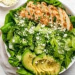 Green goddess salad in a large serving bowl with a small bowl of feta next to it.