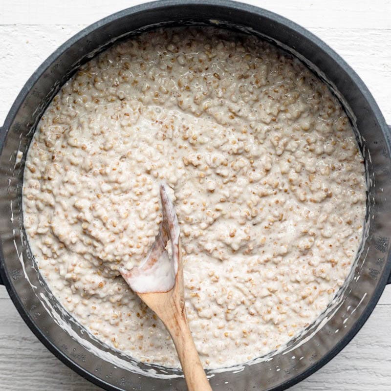 Wooden spoon showing the consistency of the overnight steel cut oats after letting sit out until room temperature.
