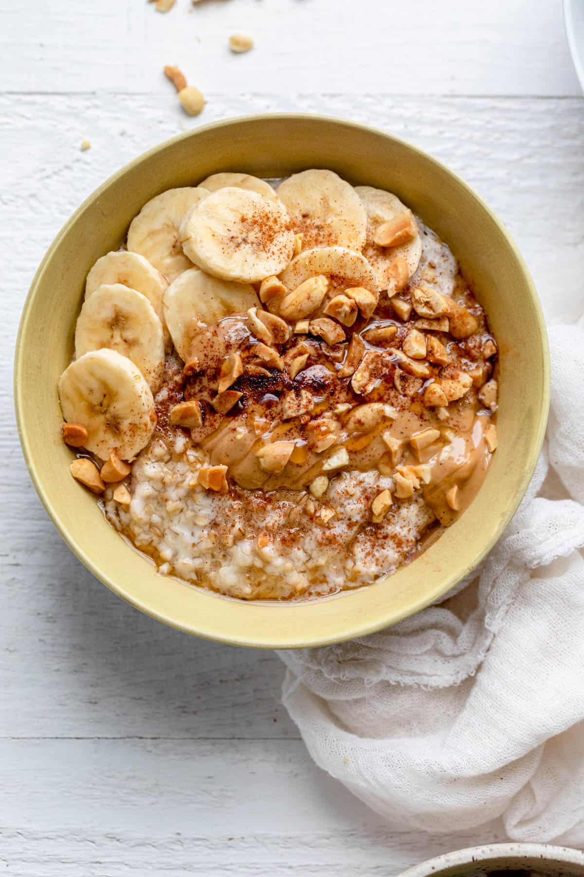 Bananas and peanut butter over oatmeal in yellow bowl