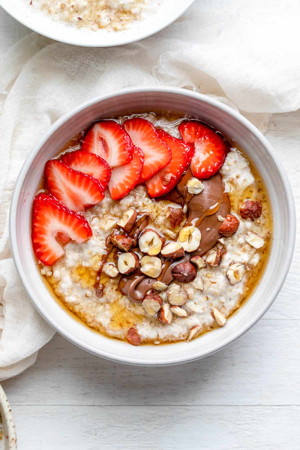 Sliced strawberries, nutella and hazelnut over oatmeal