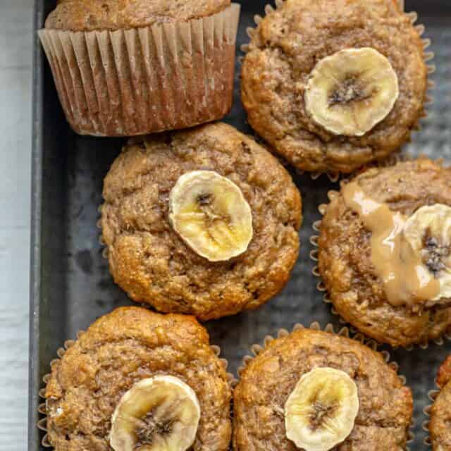 Peanut butter banana muffins in a pan topped with slices of bananas