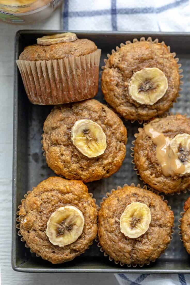 Peanut butter banana muffins in a pan topped with slices of bananas