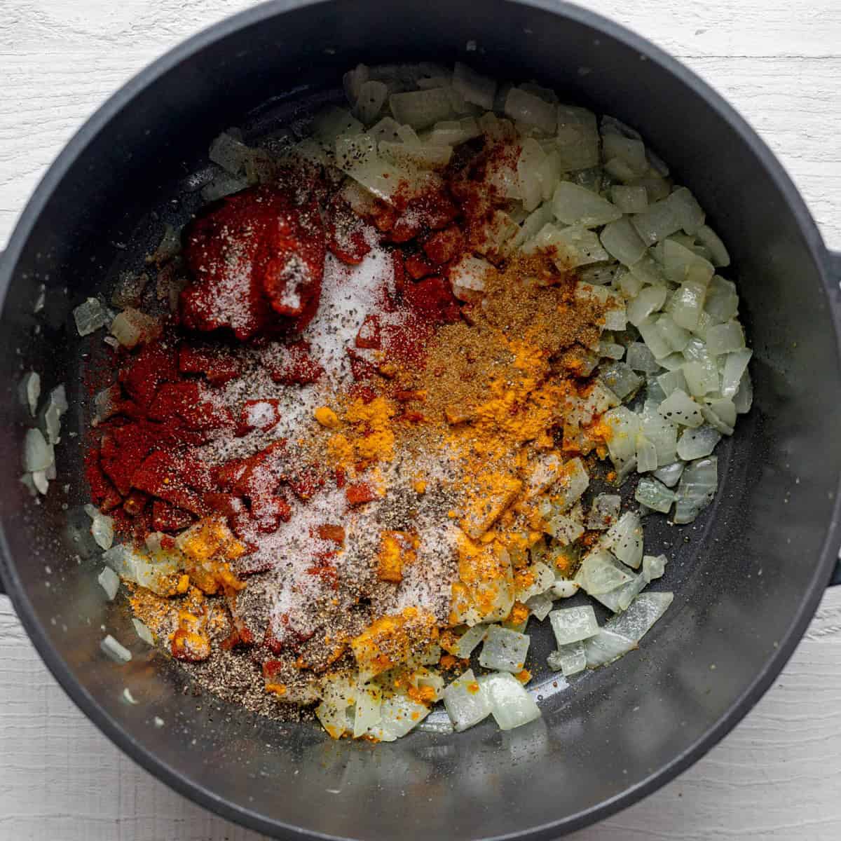Softened onions, add the garlic, tomato paste and spices in a pot.