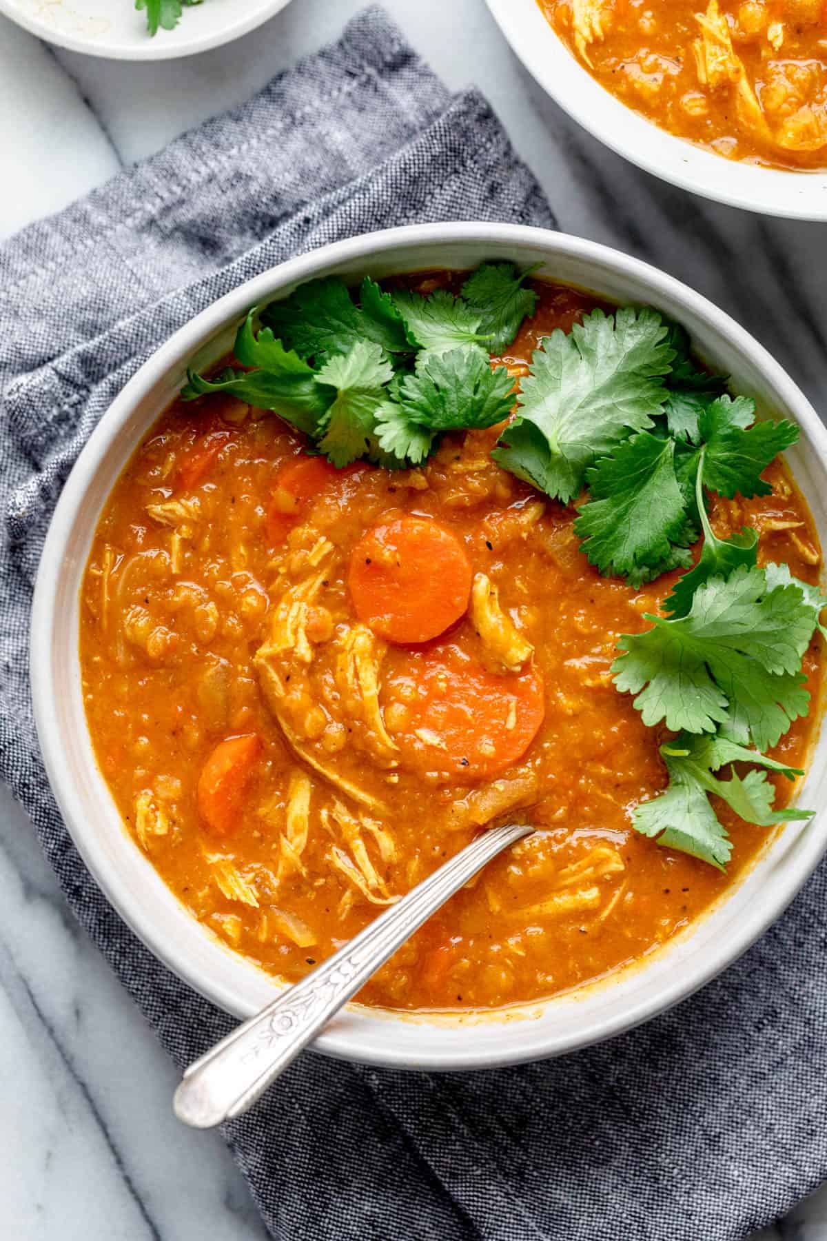 Close up of one bowl of red lentil soup garnished with cilantro