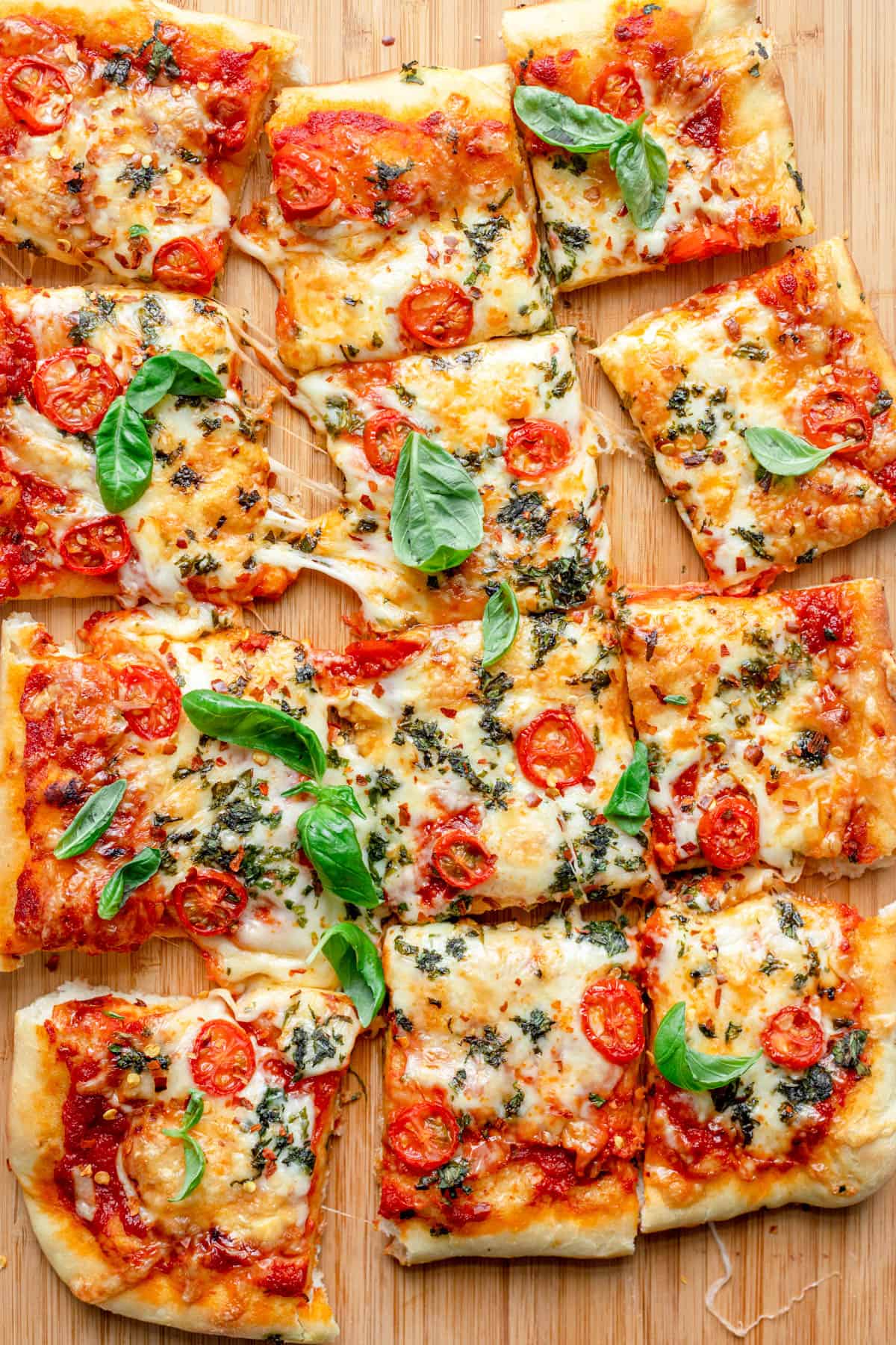 Pizza resting on wooden board, sliced into 12 pieces