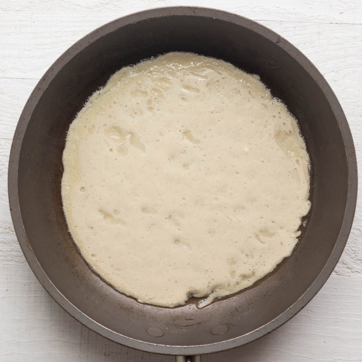 Batter in pan, showing uncooked crepe.