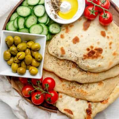 Yogurt flatbread on a board with vegetables and labneh dip