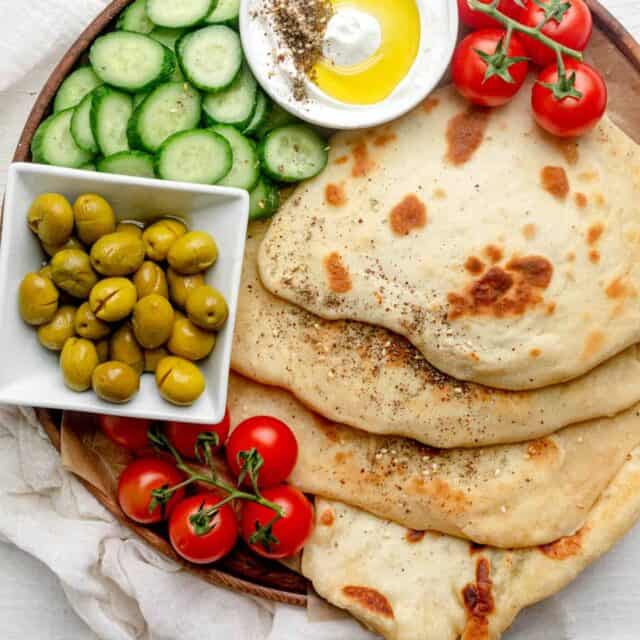 Yogurt flatbread on a board with vegetables and labneh dip