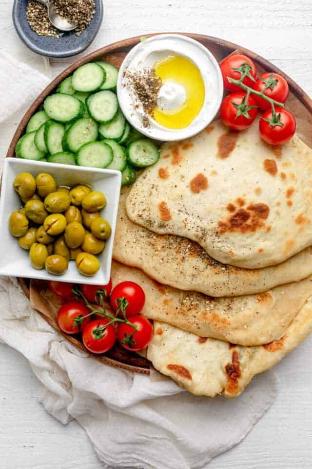 Yogurt flatbread on a board with vegetables and labneh dip