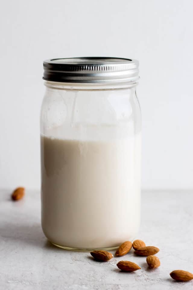 Homemade almond milk in a mason jar with a few almonds scattered