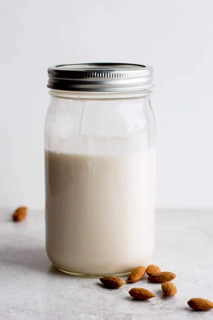 Homemade almond milk in a mason jar with a few almonds scattered