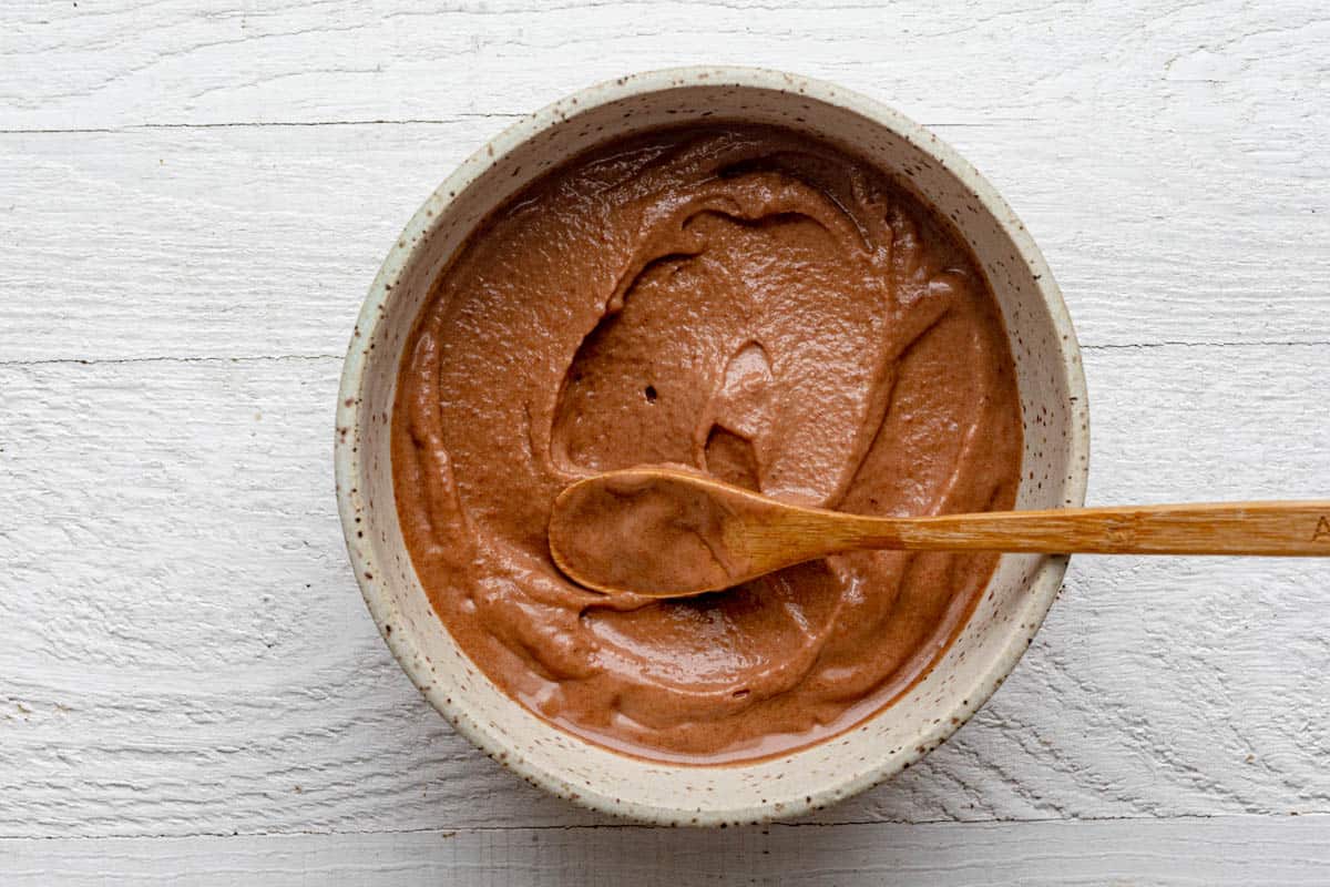 Showing the texture of the smoothie bowl in the bowl with a wooden spoon