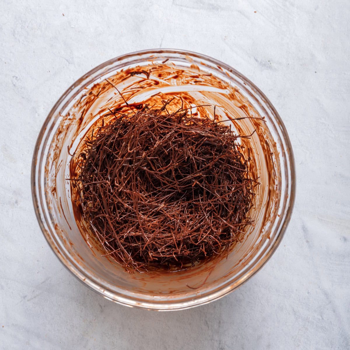 Vermicelli noodles mixed with the melted chocolate in a bowl.