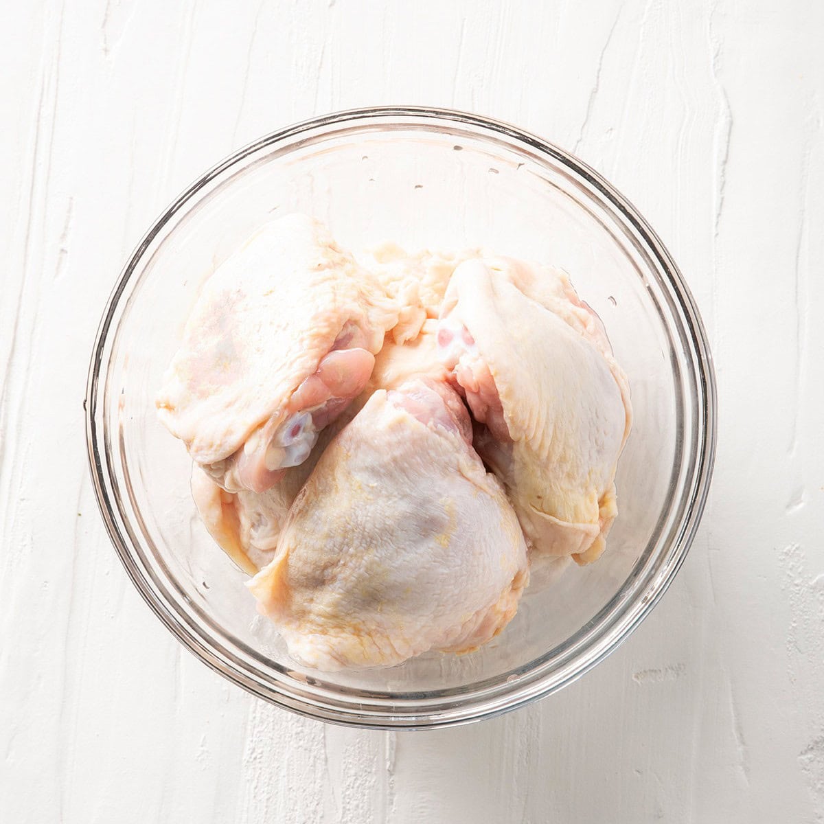 Raw chicken thighs in a bowl.